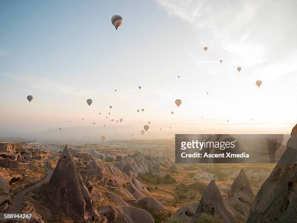 hot air balloons rise above desert landscape - cappadocia hot air balloon stock pictures, royalty-free photos & images