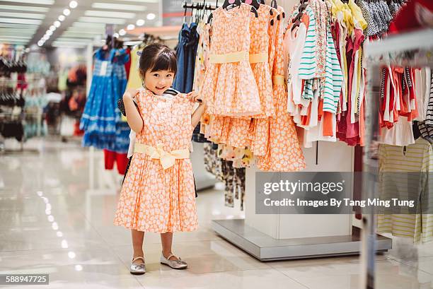 little girl trying out new dress joyfully - portrait department store stock pictures, royalty-free photos & images