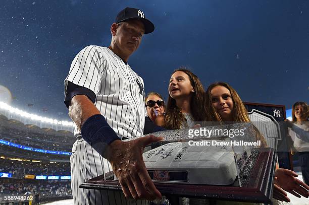 Alex Rodriguez of the New York Yankees stands with his daughters Natasha and Ella, as he looks at an autographed base given to him by the team during...