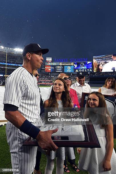 Alex Rodriguez of the New York Yankees reacts as he stands with his daughters Natasha and Ella, after being presented with an autographed base by the...