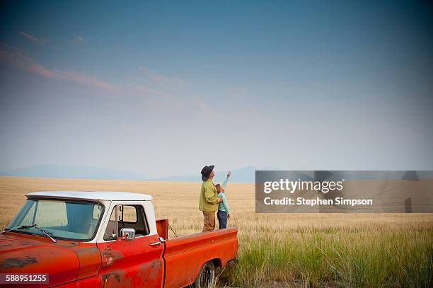 father/daughter standing back of old pickup truck - old truck imagens e fotografias de stock