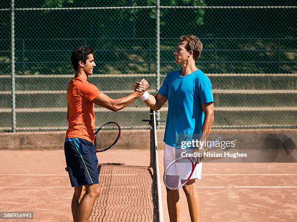 male tennis players shaking hands after match - fair stock-fotos und bilder