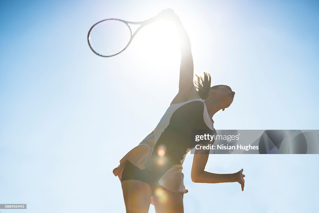 Female tennis player about to hit a serve