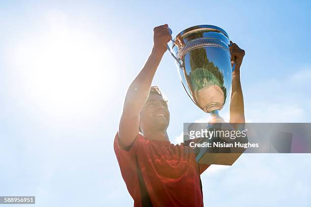 male tennis player holding up trophy - tennis championship stock pictures, royalty-free photos & images