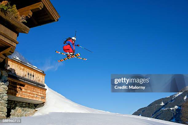 backcountry skier jumping of ski lodge. mute grab. - freestyle skiing stock-fotos und bilder