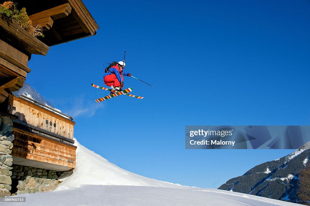 Backcountry skier jumping of ski lodge. Mute grab.