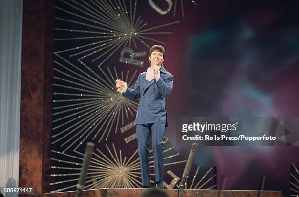 British singer Cliff Richard pictured performing on stage during the Eurovision Song Contest held at the Royal Albert Hall in London on 6th April...