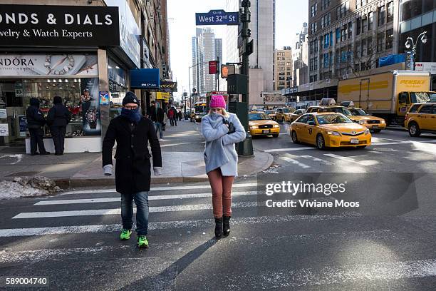 Men and Women covered and bundled trying to protect themselves from the icy polar vortex cold temperatures and wind that descended in New York and...