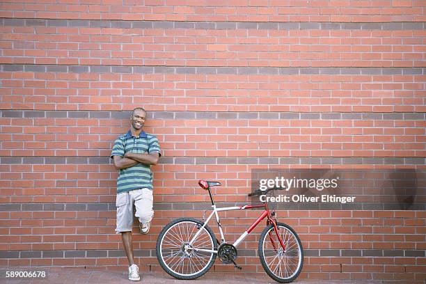 man standing against brick wall with mountain bike - oliver eltinger stock pictures, royalty-free photos & images