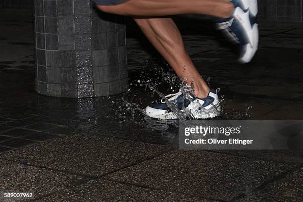 man runnign through puddle at night - oliver eltinger stock pictures, royalty-free photos & images