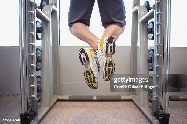 legs of man doing chin-ups - oliver eltinger stock pictures, royalty-free photos & images