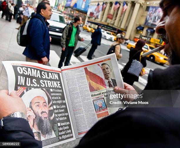 Man reading the newspaper about Osama bin Laden's capture and death. Got Him and Rot in Hell are some of the headlines.
