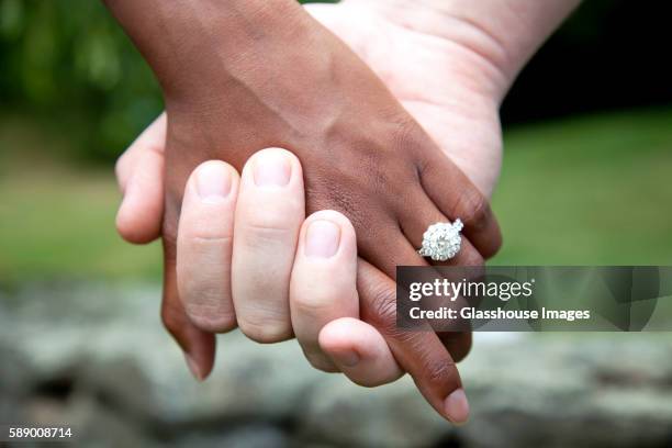 interracial couple holding hands and diamond engagement ring, close-up - anillo de compromiso fotografías e imágenes de stock