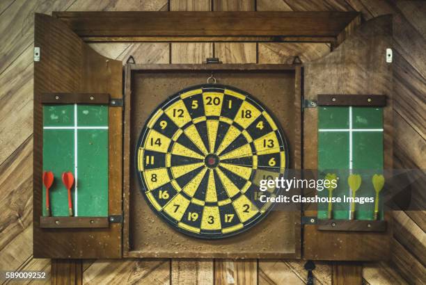 old wooden dartboard on wood-paneled basement wall - dart board stock pictures, royalty-free photos & images