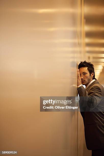 businessman leaning against a wall - oliver eltinger stock pictures, royalty-free photos & images