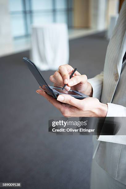 businesswoman using a personal digital assistant - oliver eltinger stock pictures, royalty-free photos & images