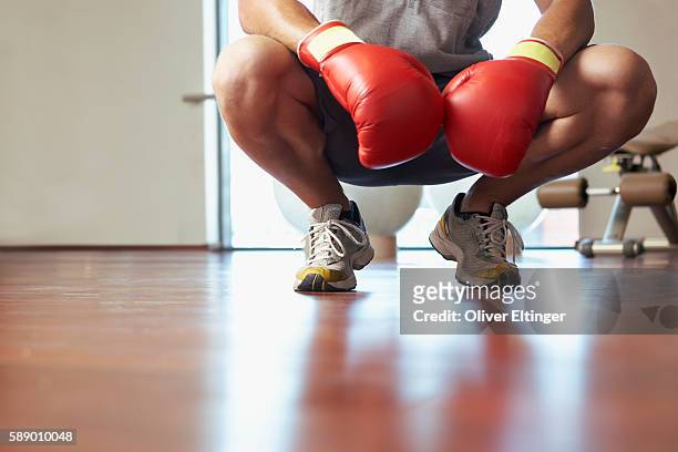 man crouching wearing boxing gloves - oliver eltinger stock-fotos und bilder