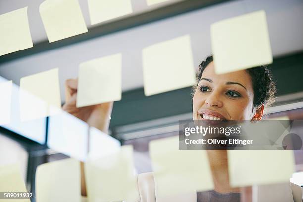 businesswoman writing on adhesive notes - oliver eltinger fotografías e imágenes de stock