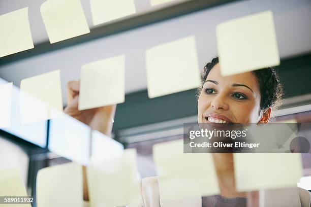 businesswoman writing on adhesive notes - oliver eltinger stock pictures, royalty-free photos & images