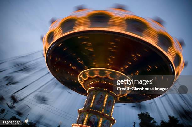 spinning carousel at dusk - atracción de feria fotografías e imágenes de stock