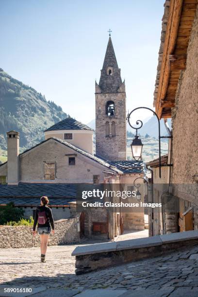 young adult woman walking through quaint village, rear view, lanslevillard, val cenis vanoise, france - サヴォア ストックフォトと画像