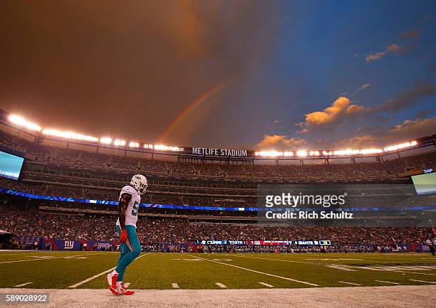 James-Michael Johnson of the Miami Dolphins walks down the sideline as a rainbow appears over head before an NFL preseason game against the New York...
