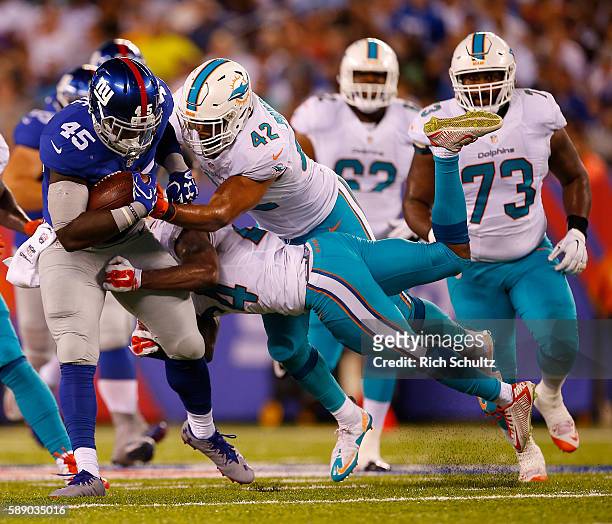 Will Tye of the New York Giants of the New York Giants runs and is tackled by Isa Abdul-Quddus and Spencer Paysinger of the Miami Dolphins during the...