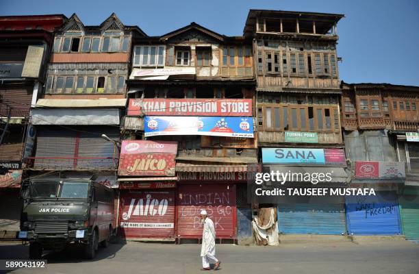 An elderly Kashmiri man walks as an Indian police armoured vehicle blocks a road towards Lal Chowk in Srinagar on August 13, 2016. Government forces...