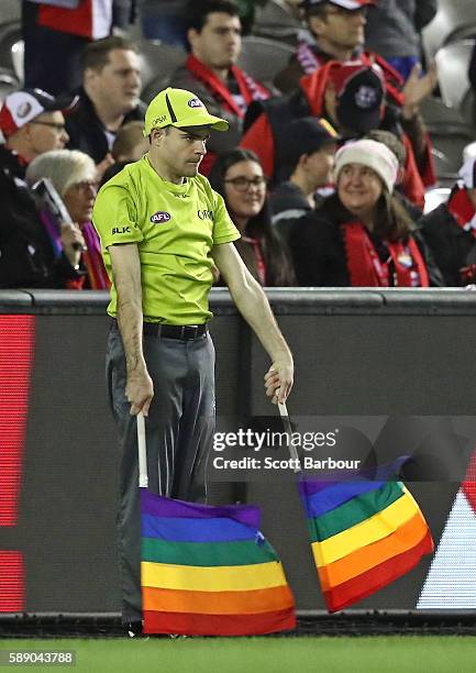 The goal umpire signals a goal using rainbow-coloured flags during the round 21 AFL match between the St Kilda Saints and the Sydney Swans at Etihad...