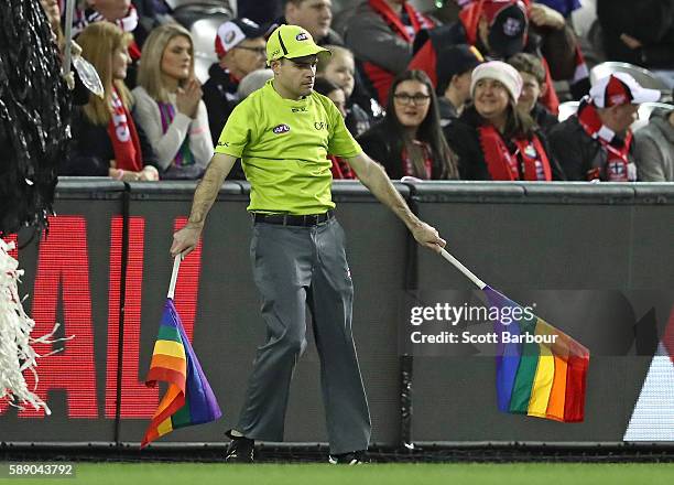 The goal umpire signals a goal using rainbow-coloured flags during the round 21 AFL match between the St Kilda Saints and the Sydney Swans at Etihad...