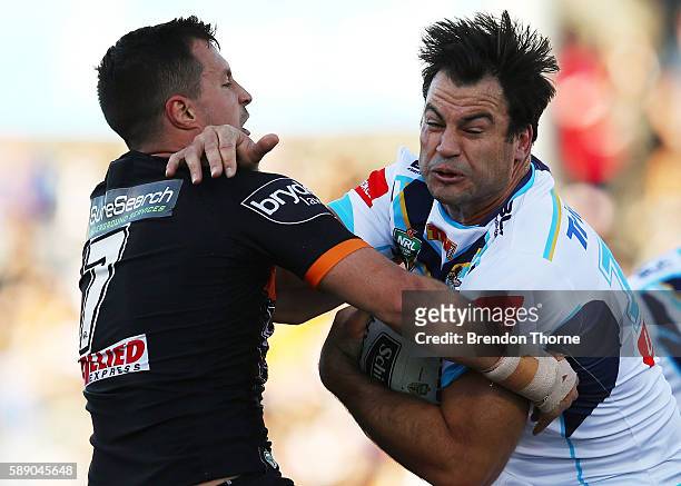 David Shillington of the Titans is tackled by Jackson Littlejohn of the Tigers during the round 23 NRL match between the Wests Tigers and the Gold...