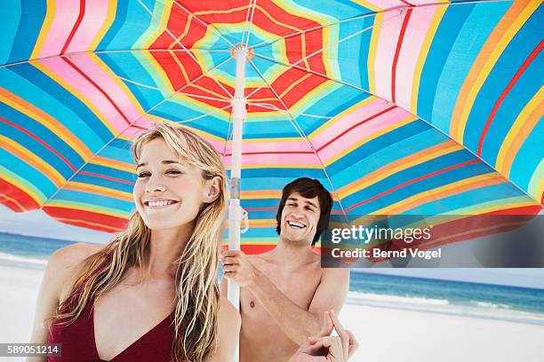 couple under beach umbrella - caballerosidad fotografías e imágenes de stock