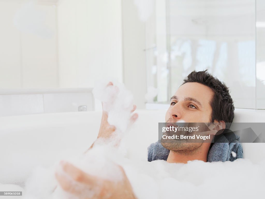 Man playing with soap suds in bubble bath