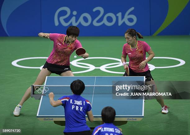 China's Ding Ning hits a shot next to China's Liu Shiwen in their women's team quarter-final table tennis match against North Korea's Ri Myong Sun...