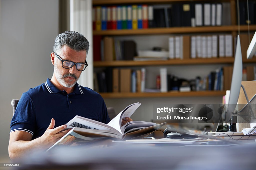 Businessman reading book at desk