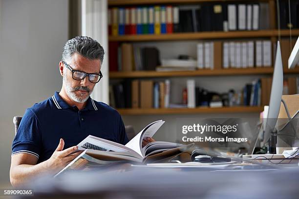 businessman reading book at desk - reading book stockfoto's en -beelden