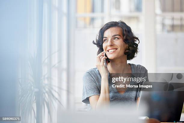 businesswoman using mobile phone in office - woman mobile phone smile smiling stock pictures, royalty-free photos & images