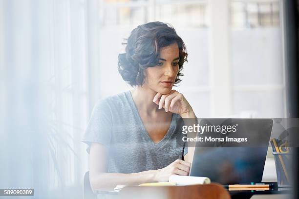businesswoman using laptop in office - one woman only fotografías e imágenes de stock