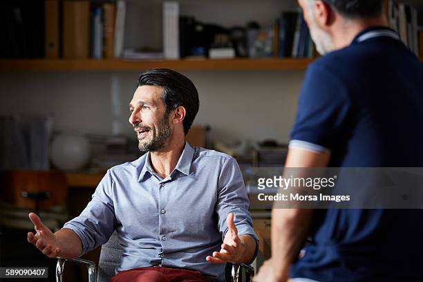 businessman gesturing while discussing in office - gesture photos et images de collection