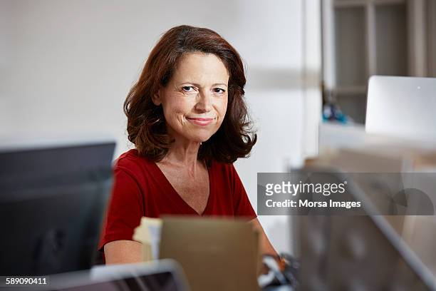 confident mature businesswoman sitting in office - vrouw 50 jaar stockfoto's en -beelden
