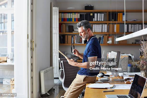 businessman using digital tablet leaning on desk - middle aged computer fotografías e imágenes de stock