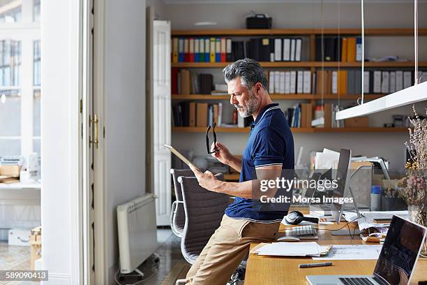 businessman using digital tablet leaning on desk - business  imagens e fotografias de stock