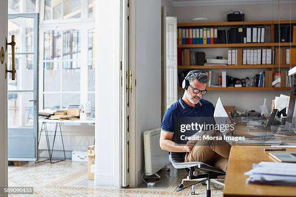 businessman examining documents at desk - auscultador equipamento áudio imagens e fotografias de stock