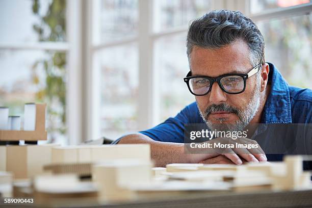 architect looking at building model in office - concentração imagens e fotografias de stock