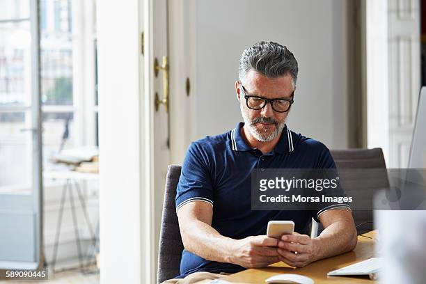 businessman using mobile phone at desk - man looking imagens e fotografias de stock
