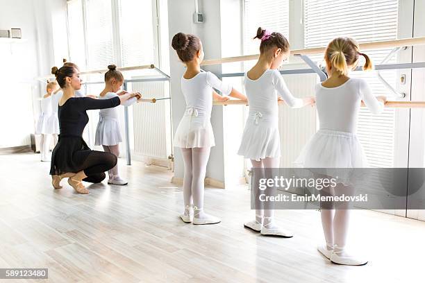 ballettlehrerin hilft mädchen mit körperhaltungen während des ballettunterrichts. - ballett mädchen stock-fotos und bilder