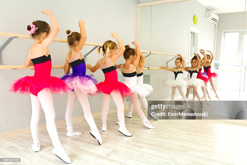 Kleine Ballerinas in Tutu mit Barre und üben Haltungen.