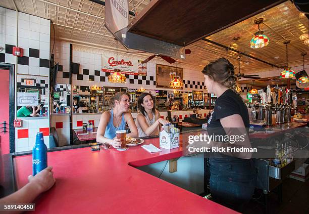 Bartender Alli Connolly at Charlie's Kitchen in Harvard Sq, Cambridge, MA on August 21, 2013 with customers Alix Easton of Brighton and Nina Krane of...