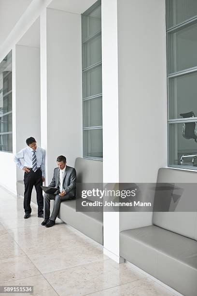 men conducting business in a hallway - business mann laptop stock pictures, royalty-free photos & images