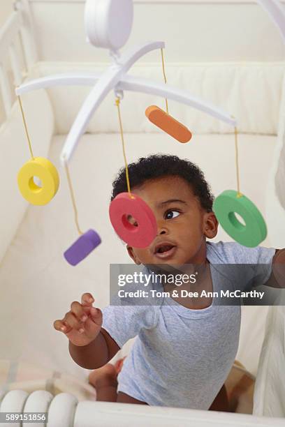 boy playing with mobile in crib - using mobile stockfoto's en -beelden